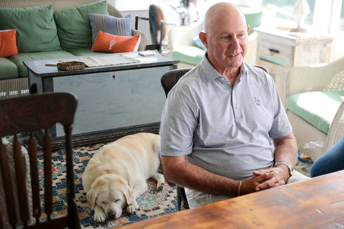 Tom Cioffi sits in his kitchen with one of his dogs behind him.
