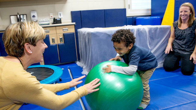 Child in a therapy session with two staff members.